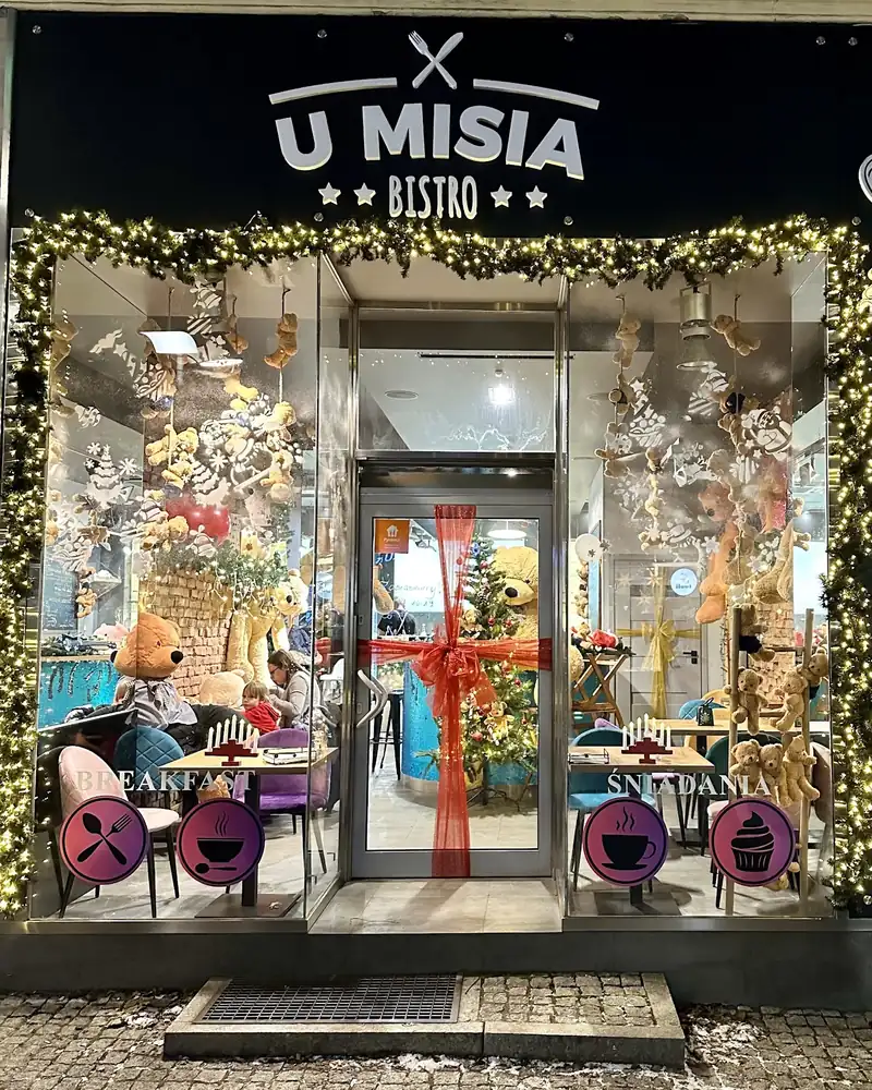 Witryna z czarnym szyldem U Misia Bistro i girlandą