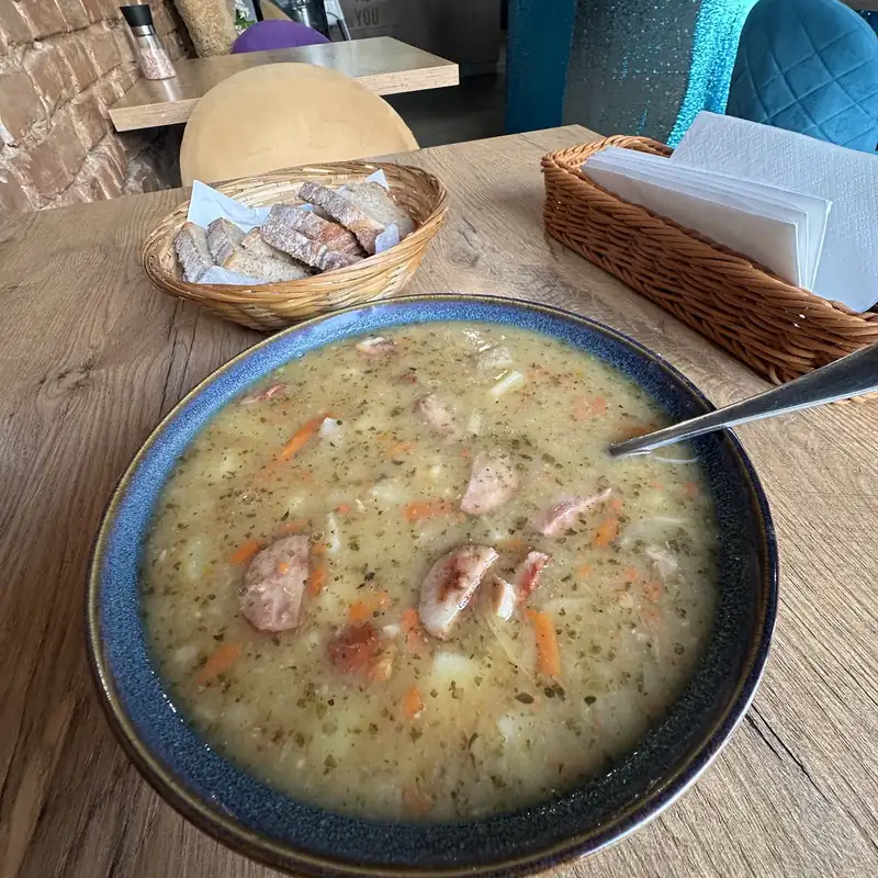 Zupa z kiełbasą w granatowej misce na drewnianym stole